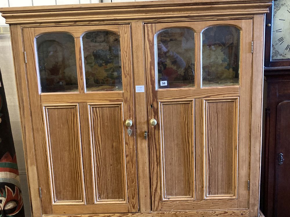 An early 19th century stripped pine cupboard, fitted with a pair of part glazed panelled doors, over three drawers and cupboards, width